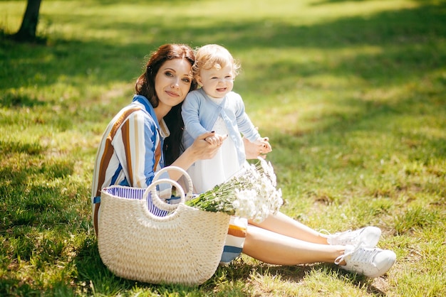 Hermosa chica con una pequeña hija en brazos en el parque