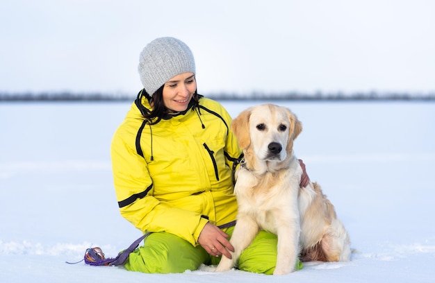 Hermosa chica con perro perdiguero joven encantador afuera en invierno