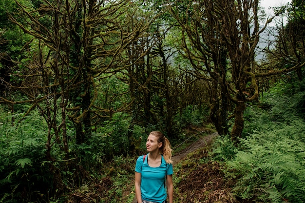 Hermosa chica de pie de pie en el bosque verde