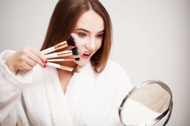 Hermosa chica con piel sana haciendo maquillaje