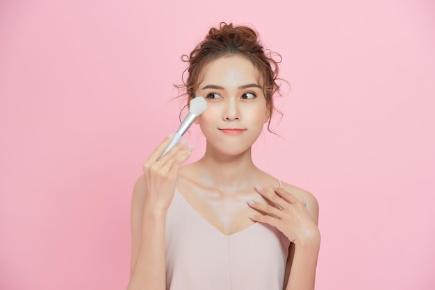 Hermosa chica con pincel de polvo cosmético para maquillaje