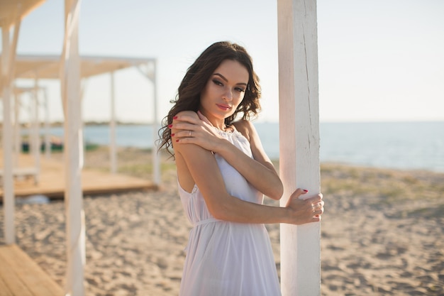 Hermosa chica en la playa con un vestido blanco.