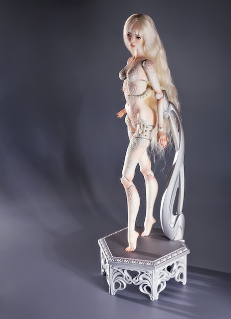 Hermosa chica de porcelana sobre fondo gris. Muñeca bjd