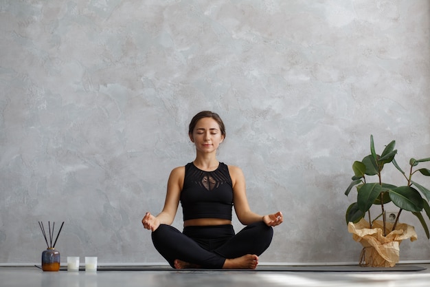 Hermosa chica practicando pose de yoga fácil, sukhasana.