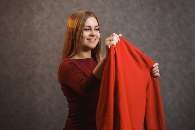 Hermosa chica se prueba un suéter rojo