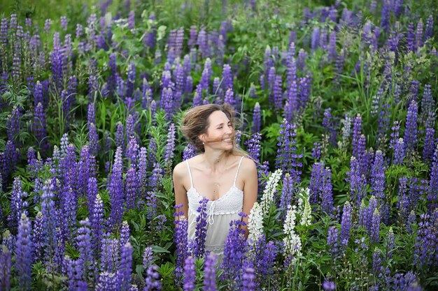 Hermosa chica con un ramo de flores azules en la naturaleza en verano