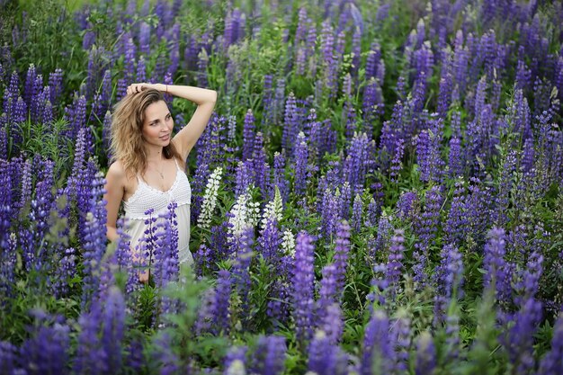 Hermosa chica con un ramo de flores azules en la naturaleza en verano