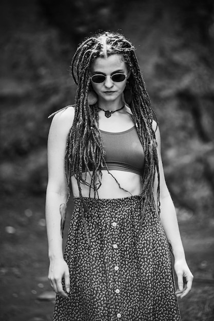 Hermosa chica con rastas vestida estilo hippie posa al aire libre