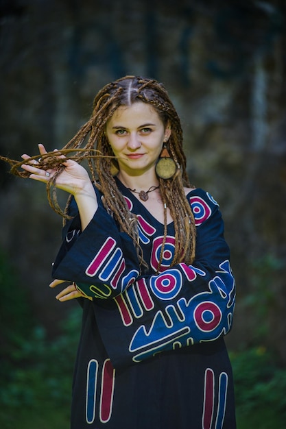 Hermosa chica con rastas vestida estilo hippie posa al aire libre