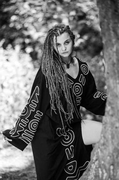 Hermosa chica con rastas vestida estilo hippie posa al aire libre