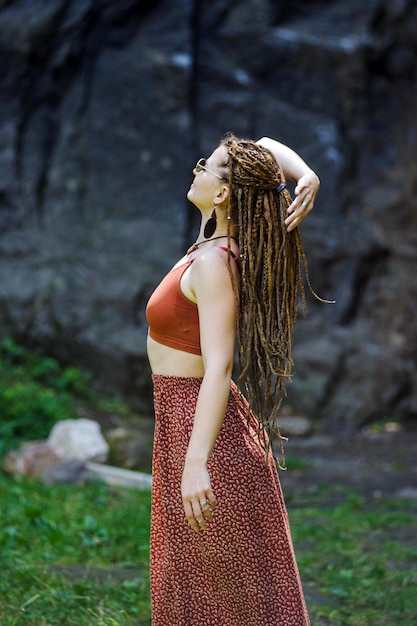 Hermosa chica con rastas vestida estilo hippie posa al aire libre