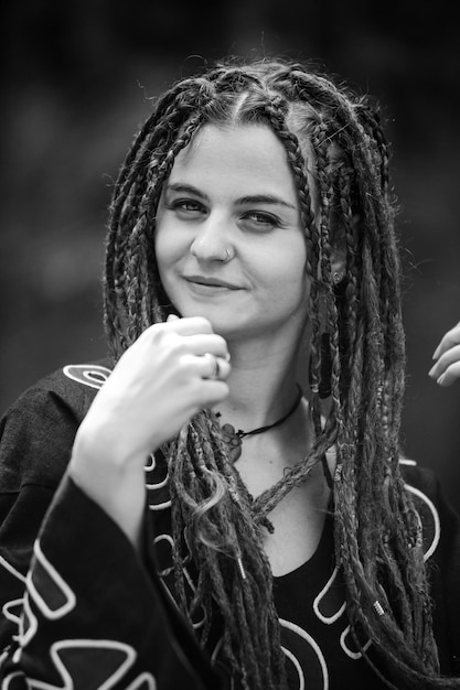 Hermosa chica con rastas vestida estilo hippie posa al aire libre