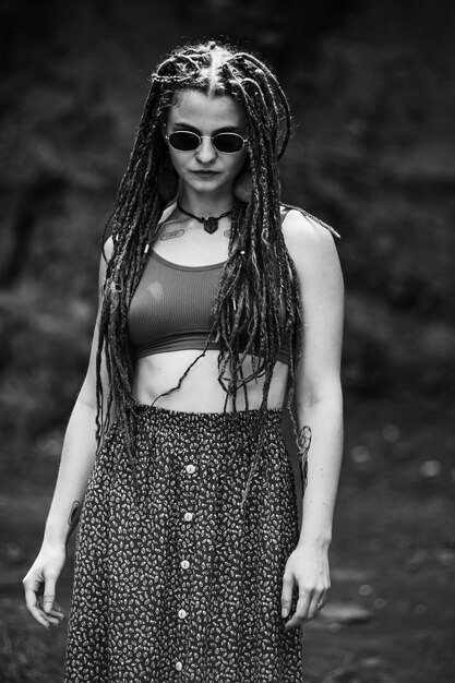 Hermosa chica con rastas vestida estilo hippie posa al aire libre