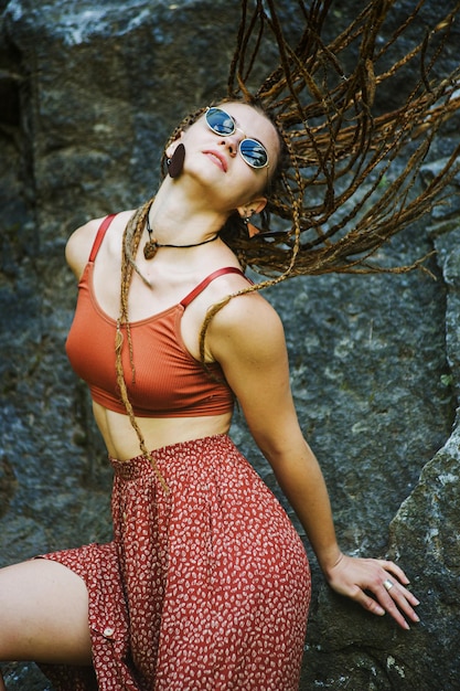 Hermosa chica con rastas vestida estilo hippie posa al aire libre