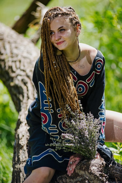 Hermosa chica con rastas vestida estilo hippie posa al aire libre