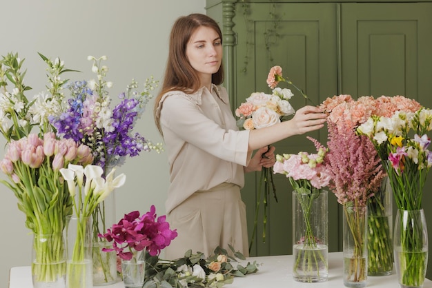 Hermosa chica recoge un ramo de flores en una floristería