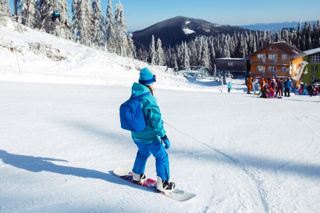 Una hermosa chica en ropa de invierno está montando una tabla de snowboard.