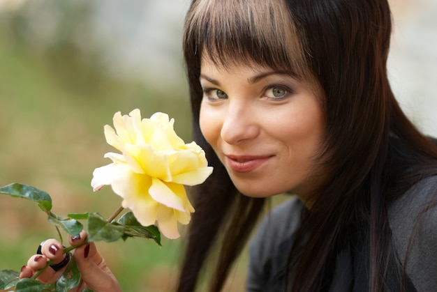 Hermosa chica con rosa amarilla, fondo suave