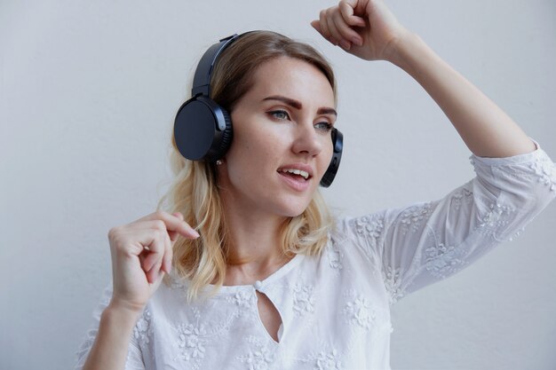 Hermosa chica rubia con auriculares. Le gusta escuchar música, cantar y divertirse.