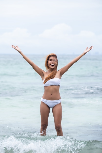 Hermosa chica rubia en bikini blanco en el mar.