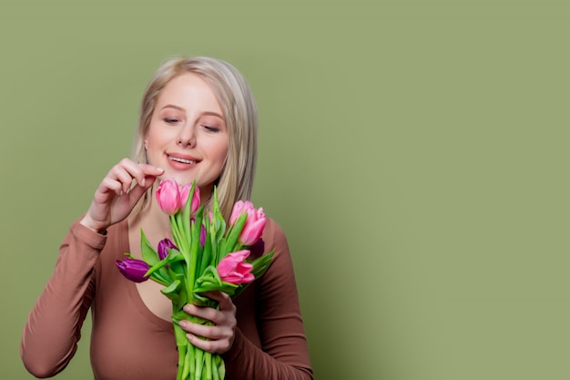 Hermosa chica rubia en blusa marrón con tulipanes