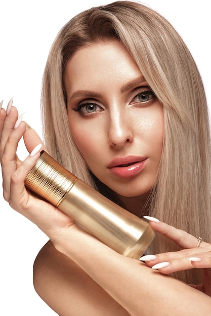 Hermosa chica rubia con un cabello perfecto y maquillaje clásico con productos cosméticos rostro de belleza y