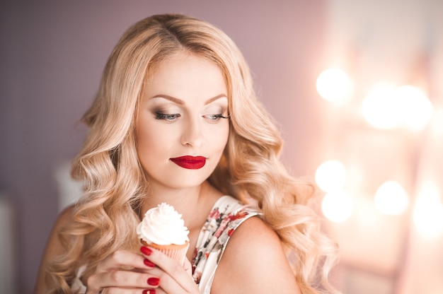 Hermosa chica rubia con cabello rizado con cupcake cremoso