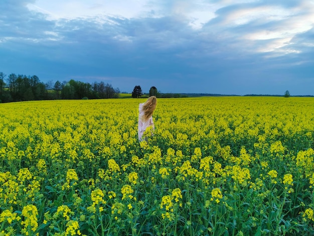 Hermosa chica rubia en un campo de violación antes de la tormenta chica y flores