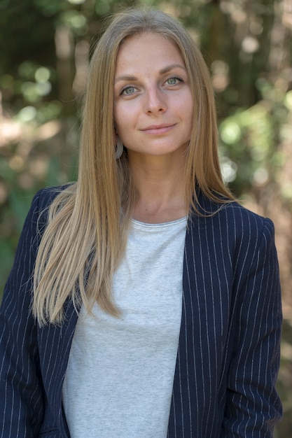 Hermosa chica rubia caucásica en un traje de negocios en el fondo de la naturaleza. Un retrato de una mujer joven