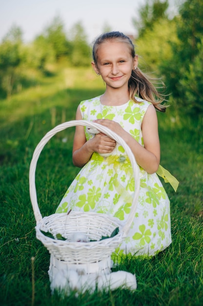 hermosa chica rubia con conejitos sentados en la hierba verde. conejos de vacaciones conejo de Pascua