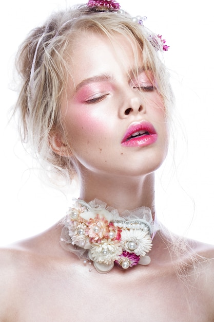 Hermosa chica rubia de moda con flores en el cuello y en el pelo, maquillaje desnudo mojado