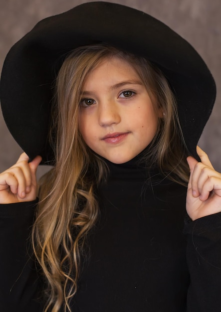 una hermosa chica rubia de pelo largo con un suéter negro y un sombrero negro