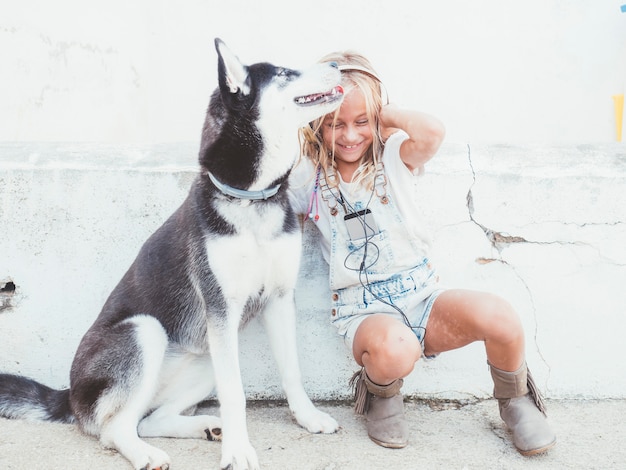Hermosa chica rubia posa con mascota Husky siberiano