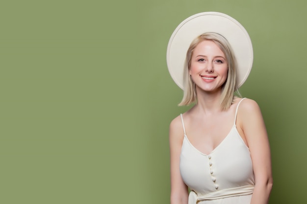 Hermosa chica rubia con sombrero blanco y vestido