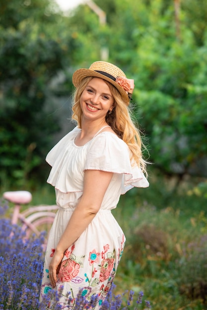 Hermosa chica rubia en el sombrero cerca de arbustos de lavanda