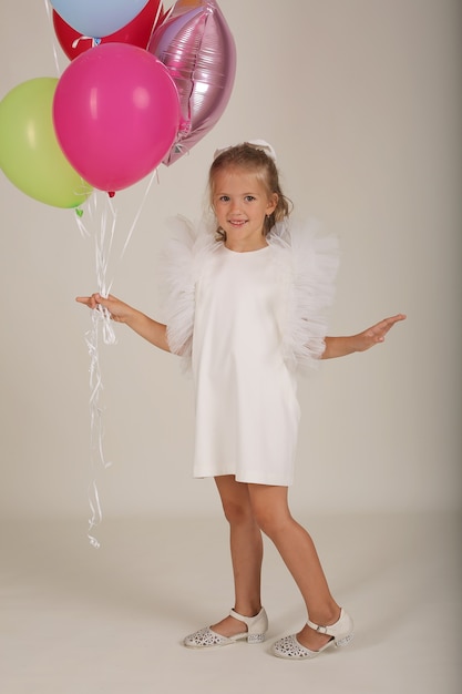 Hermosa chica rubia con un vestido blanco con globos en sus manos cumpleaños festivo