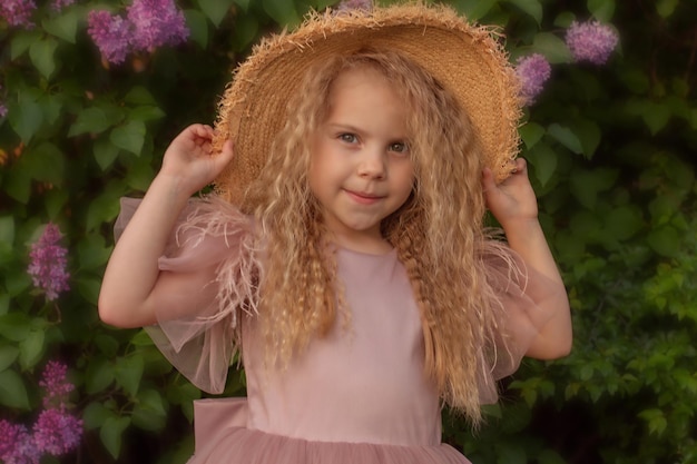 Hermosa chica rubia con un vestido rosa con el pelo largo en un sombrero de paja