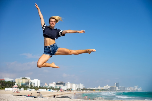 Hermosa chica salta con South Beach en el fondo, Miami Beach. Florida. Concepto de felicidad y libertad.