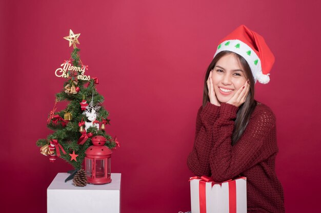 Hermosa chica de Santa Claus en estudio sobre fondo rojo, concepto de Navidad