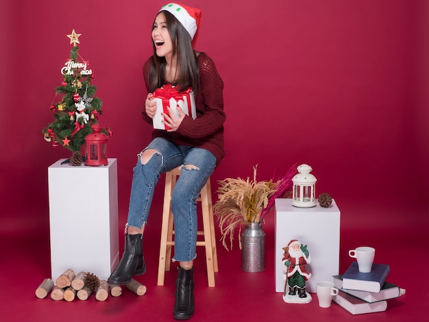 Hermosa chica de Santa Claus en estudio sobre fondo rojo, concepto de Navidad