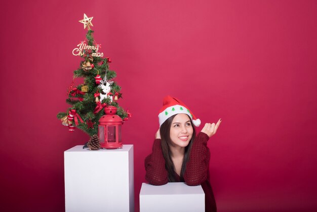 Hermosa chica de Santa Claus en estudio sobre fondo rojo, concepto de Navidad