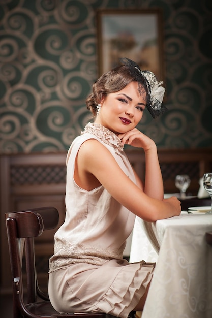 Hermosa chica sentada en una mesa en el restaurante