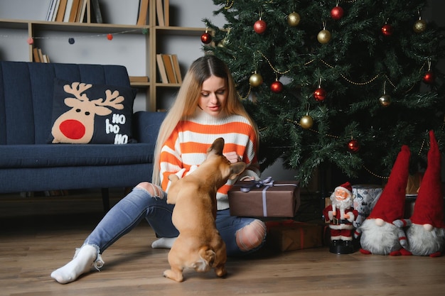 Hermosa chica sentada en el sofá con un perro en el fondo de Navidad