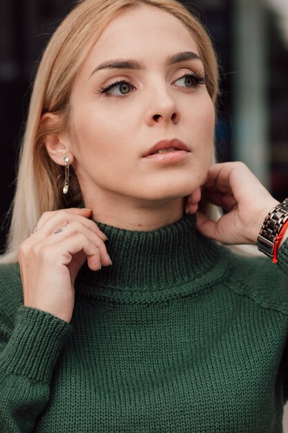 Hermosa chica sexy de pie en la calle con un traje verde de punto