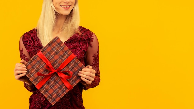 Una hermosa chica sexy con un sombrero de año nuevo y un vestido gris, mantenga en las manos los regalos. Celebración de Navidad o año nuevo