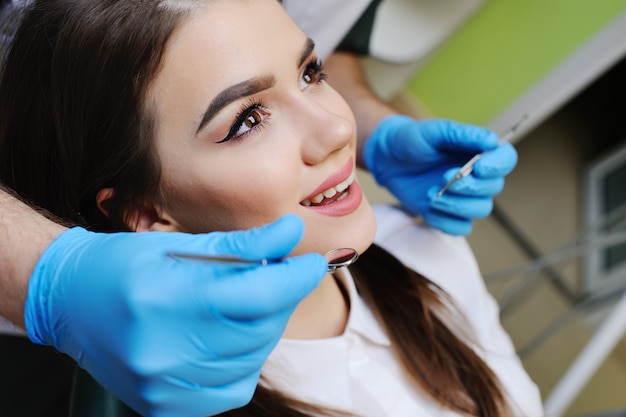 Hermosa chica en el sillón dental en el examen en el dentista