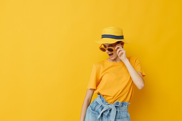 Hermosa chica en un sombrero amarillo Ropa casual de estilo juvenil en gafas de sol Estilo de vida inalterado