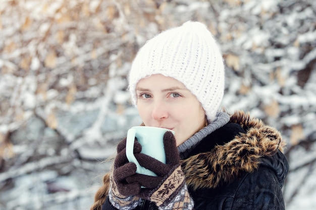 Hermosa chica en un sombrero blanco con guantes y con una taza de té fondo blanco nevado