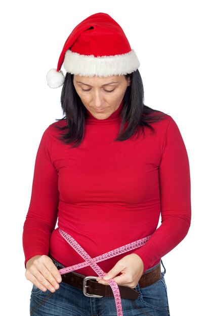 Hermosa chica con sombrero de Navidad midiendo su cintura sobre un fondo blanco