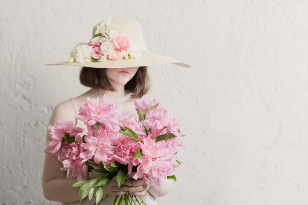 Hermosa chica con sombrero de paja con flores de verano